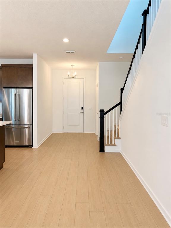 A kitchen area with stainless steel appliances, light wood flooring, and a staircase with black railings — 1741 CROWNCREST DRIVE, APOPKA, FL