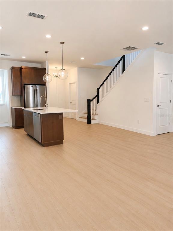 A kitchen with dark wood cabinets and a white island sits beside a staircase — 1741 CROWNCREST DRIVE, APOPKA, FL