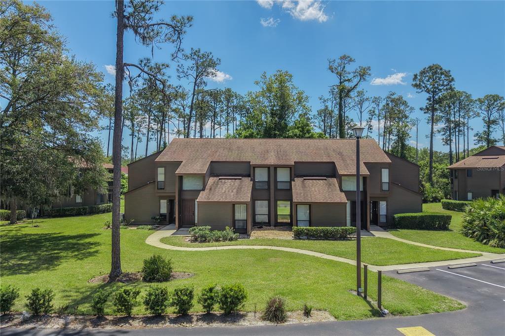 A two-story brown apartment building with a shingled roof sits on a grassy lawn — 16 HEMBURY LANE UNIT 16, PALM COAST, FL