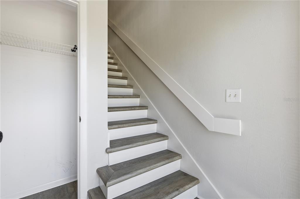 A staircase with wood-look treads and white risers sits next to a closet — 16 HEMBURY LANE UNIT 16, PALM COAST, FL