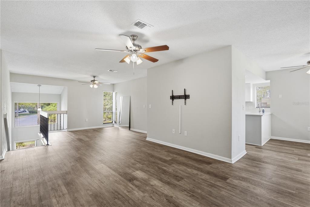 An open-concept living area features light gray walls, wood-look flooring, and two ceiling fans — 16 HEMBURY LANE UNIT 16, PALM COAST, FL