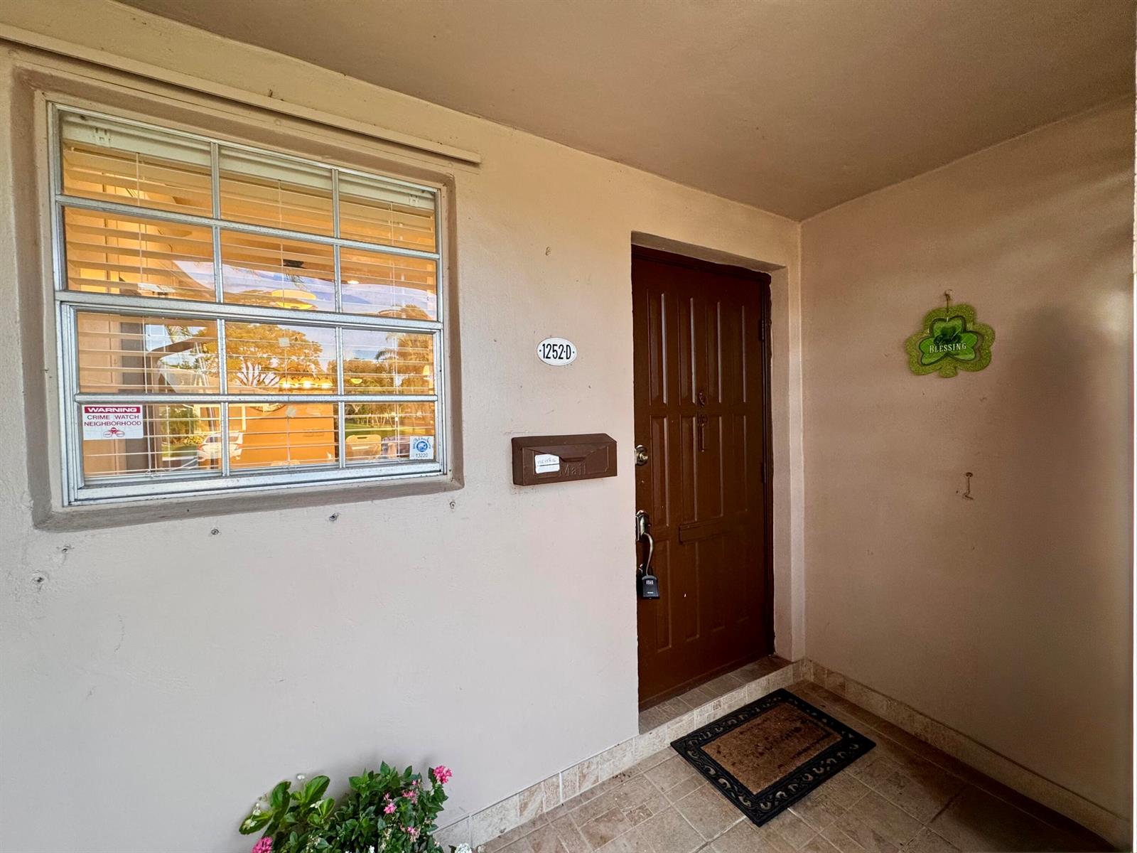 A brown front door with a mailbox and a window with blinds on a porch — 1252 Club Drive W # D, Delray Beach FL 33445, DELRAY BEACH, FL