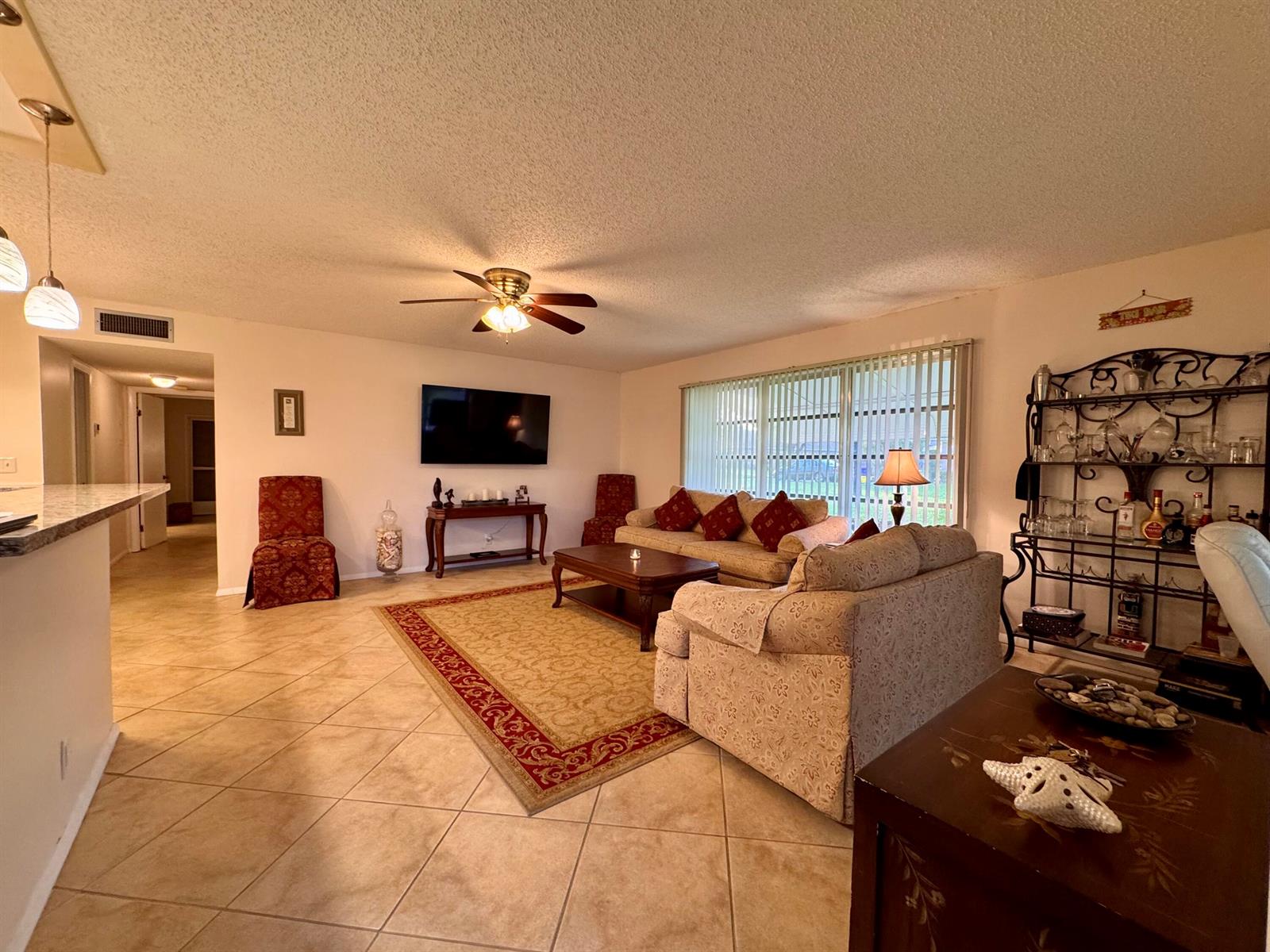 A living room features tile flooring, a ceiling fan, a television, and a beige sofa — 1252 Club Drive W # D, Delray Beach FL 33445, DELRAY BEACH, FL