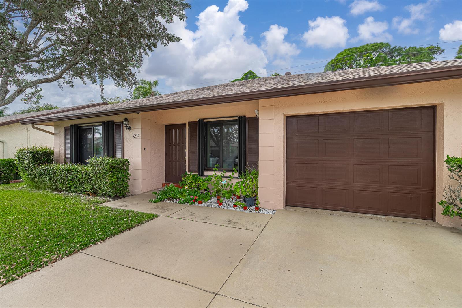 A single-story house with a peach-colored exterior, brown garage door, and a front lawn — 6335 Tall Cypress Circle, FL 33463, FL