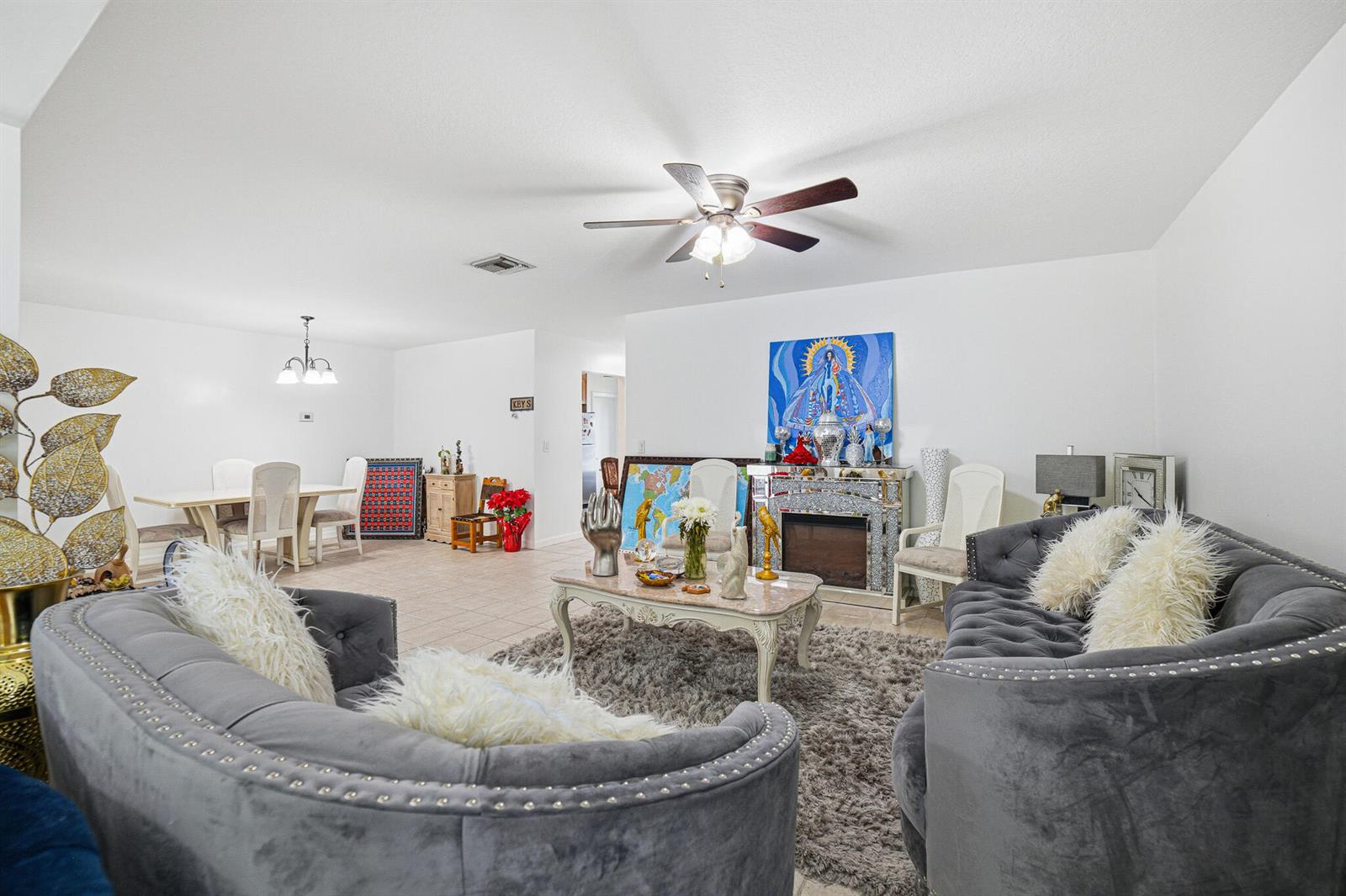 A living room features two grey tufted sofas, a coffee table, and a fireplace — 6335 Tall Cypress Circle, FL 33463, FL