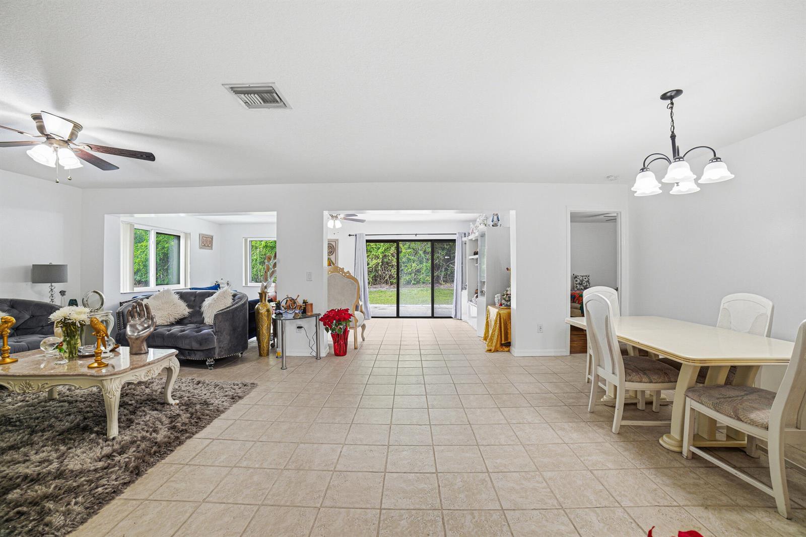 A bright, open-concept living and dining area features tile flooring and sliding glass patio doors — 6335 Tall Cypress Circle, FL 33463, FL