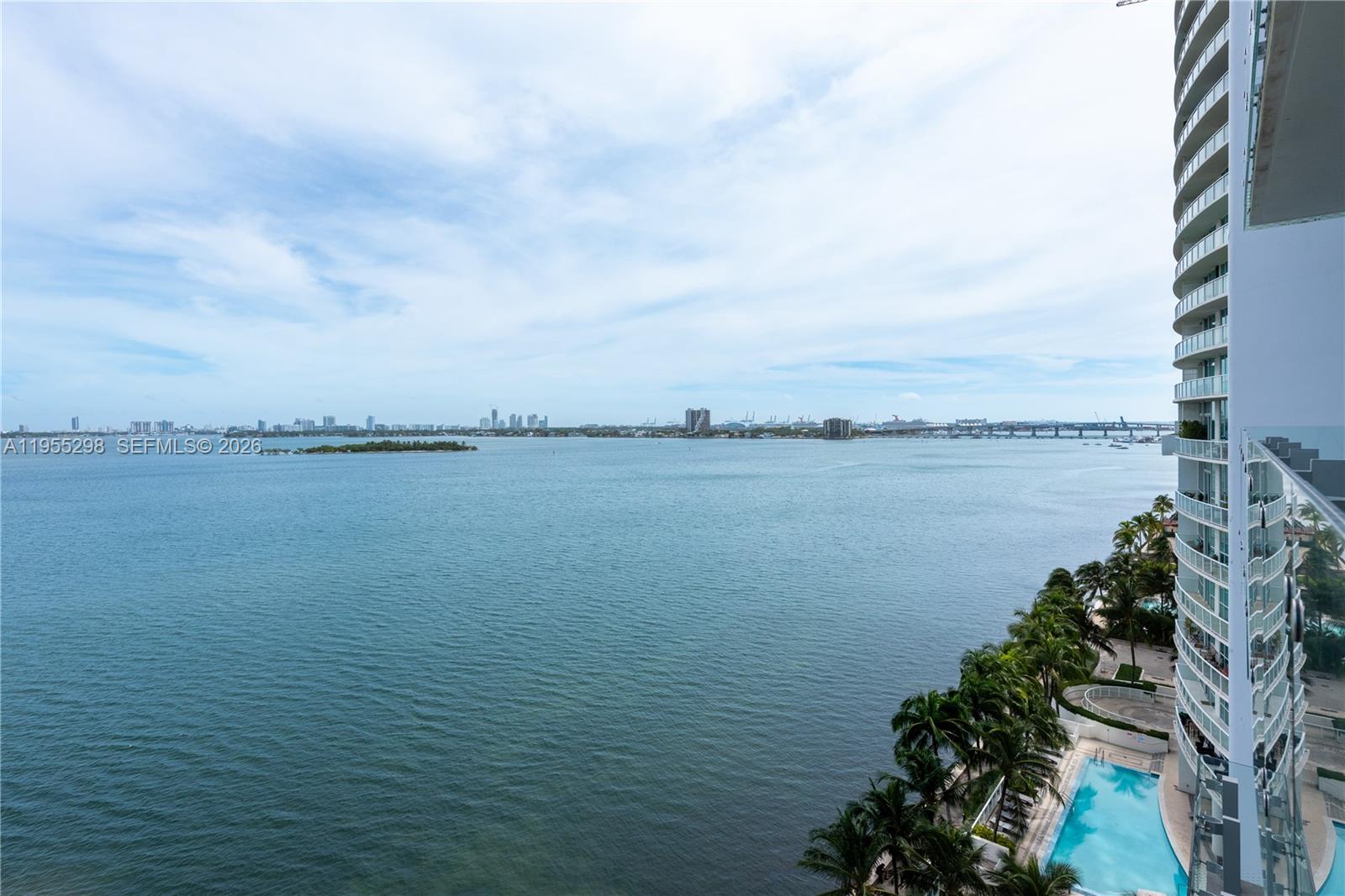 A high-angle view shows a balcony overlooking a bay, a swimming pool, and palm trees — 700 NE 26th Ter # 903, Miami FL 33137, MIAMI, FL