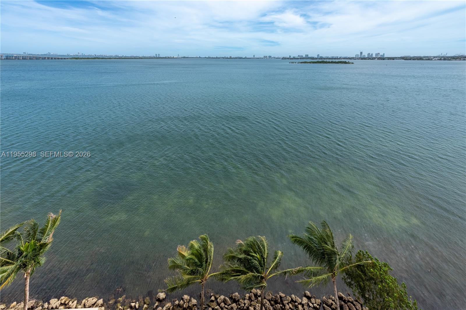 A high-angle view shows palm trees along a rocky shoreline overlooking a large bay — 700 NE 26th Ter # 903, Miami FL 33137, MIAMI, FL