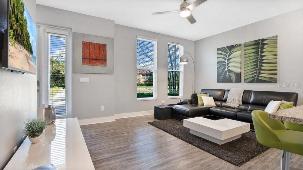 A modern living room features a black leather sectional, white coffee table, and gray flooring — 1861 HOUSTON STREET, KISSIMMEE, FL