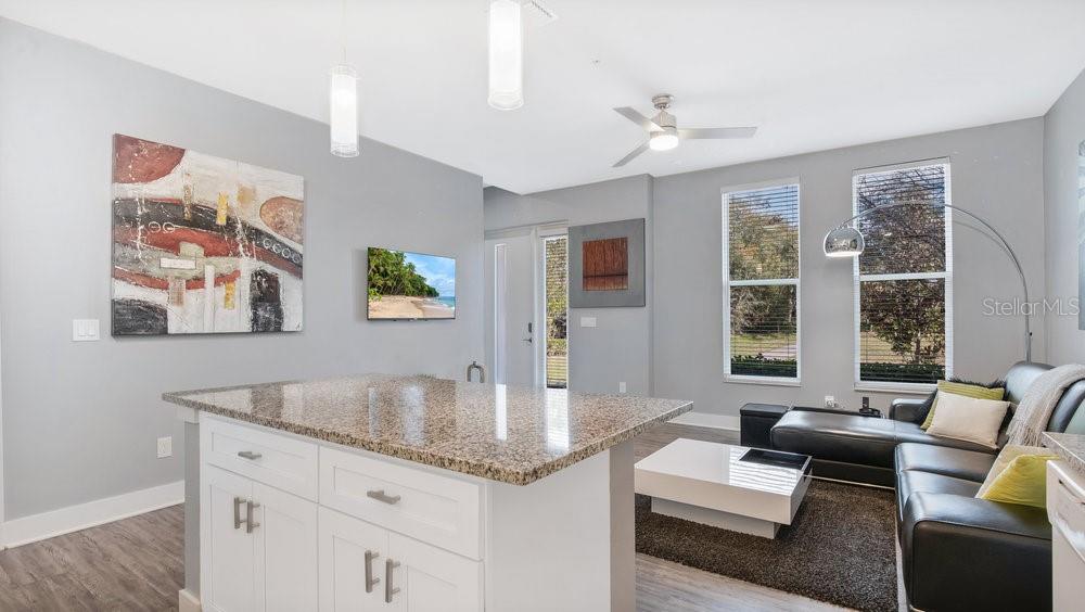 A kitchen island with granite countertops overlooks a living area with a leather sectional sofa — 1861 HOUSTON STREET, KISSIMMEE, FL
