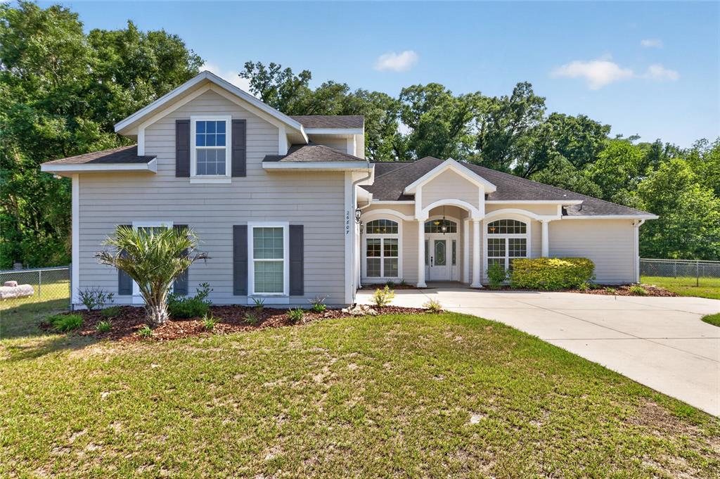 A two-story house with light-colored siding, a concrete driveway, and a covered front entryway — 26807 SW 20TH PLACE, NEWBERRY, FL