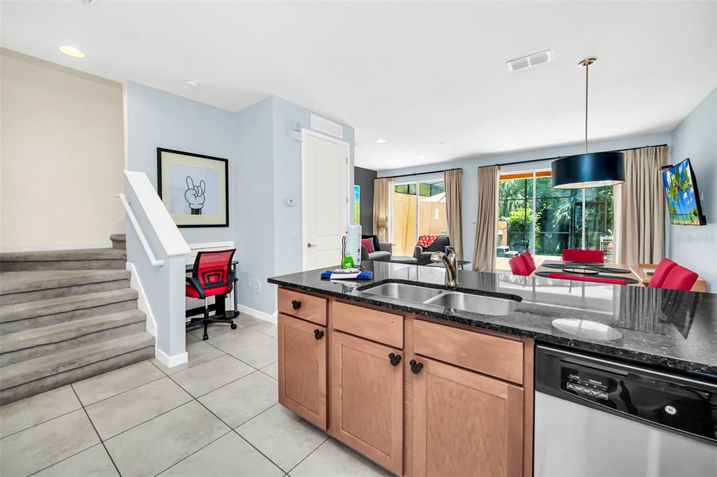A kitchen with wood cabinets and granite countertops overlooks a dining area and living space — 2607 CORVETTE LANE, KISSIMMEE, FL