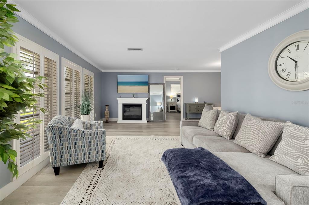 A living room features a gray sectional sofa, a patterned armchair, and a white fireplace — 3304 SPRING MILL CIRCLE, SARASOTA, FL