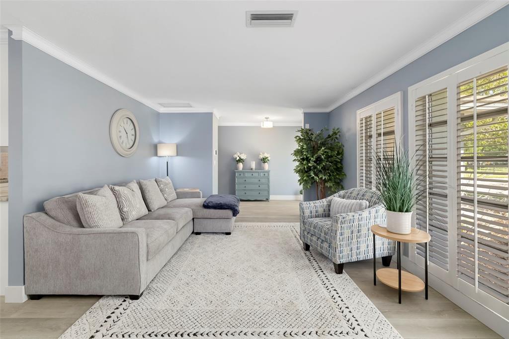 A living room features light blue walls, a gray sectional sofa, and a patterned armchair — 3304 SPRING MILL CIRCLE, SARASOTA, FL