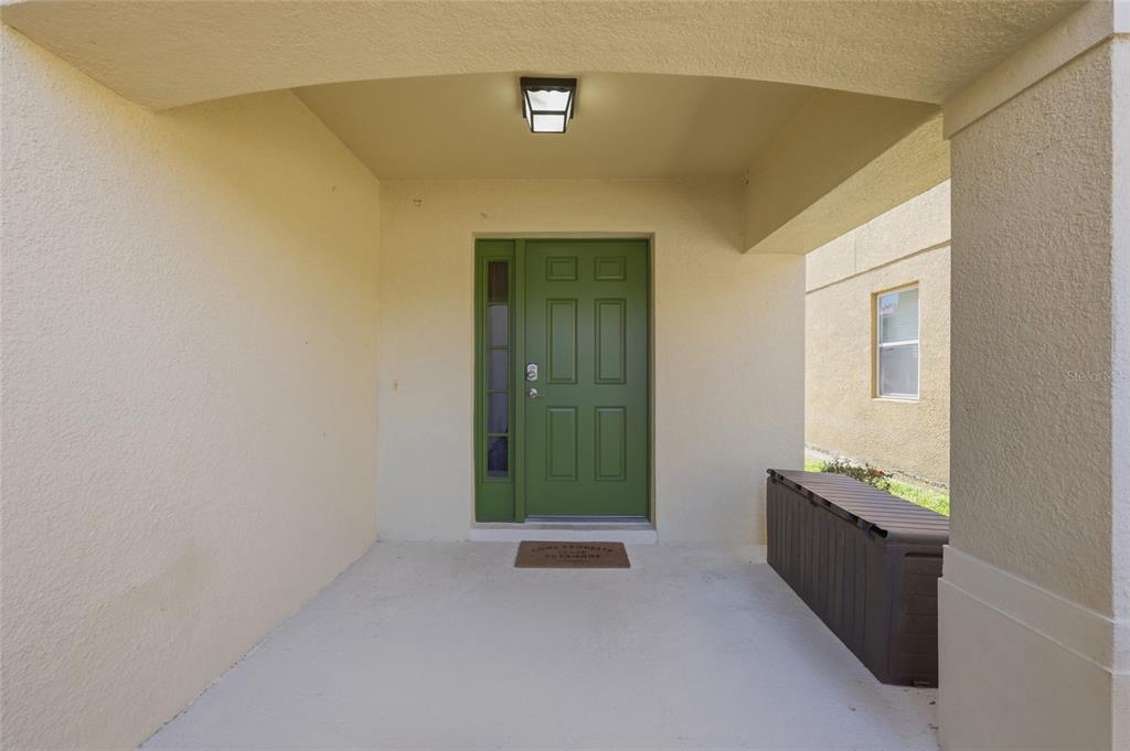 A covered entryway features a green front door with a side window and a storage bin — 2620 SANTOSH COVE, KISSIMMEE, FL