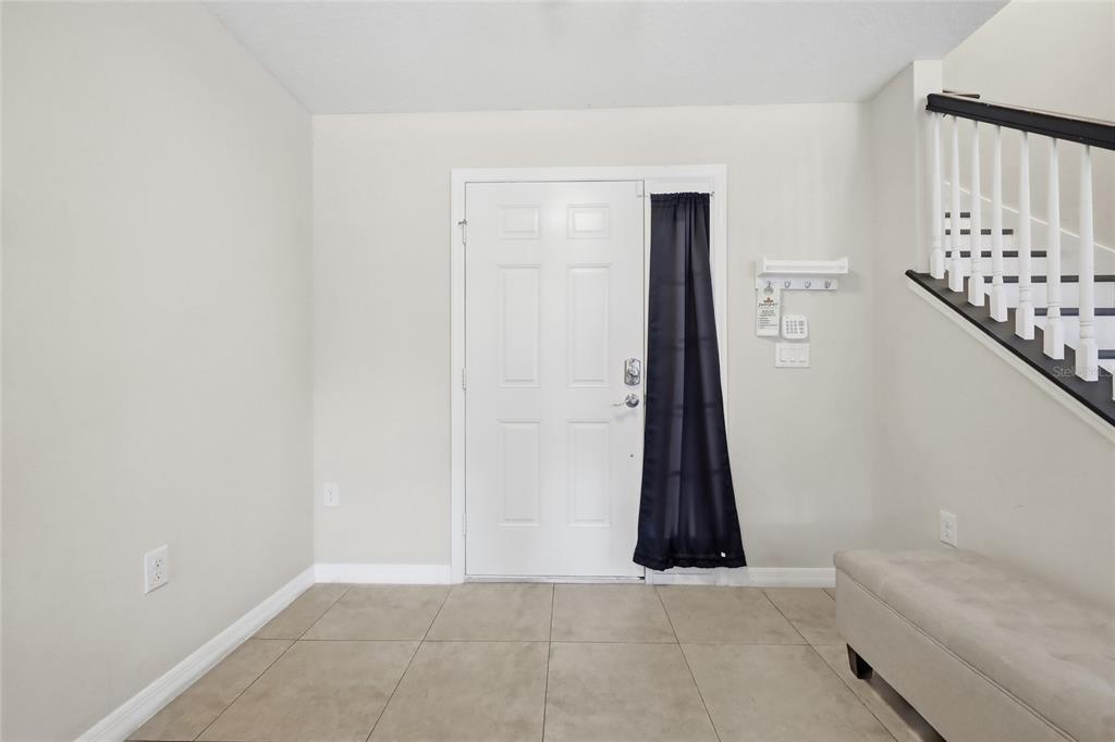 An entryway features a white front door with a side window, tile flooring, and stairs — 2620 SANTOSH COVE, KISSIMMEE, FL