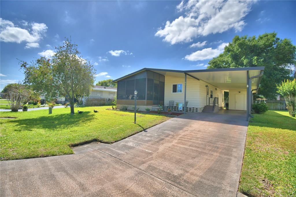 A single-story house with a screened-in porch, a carport, and a concrete driveway — 447 VILLAGE CIRCLE SW, WINTER HAVEN, FL