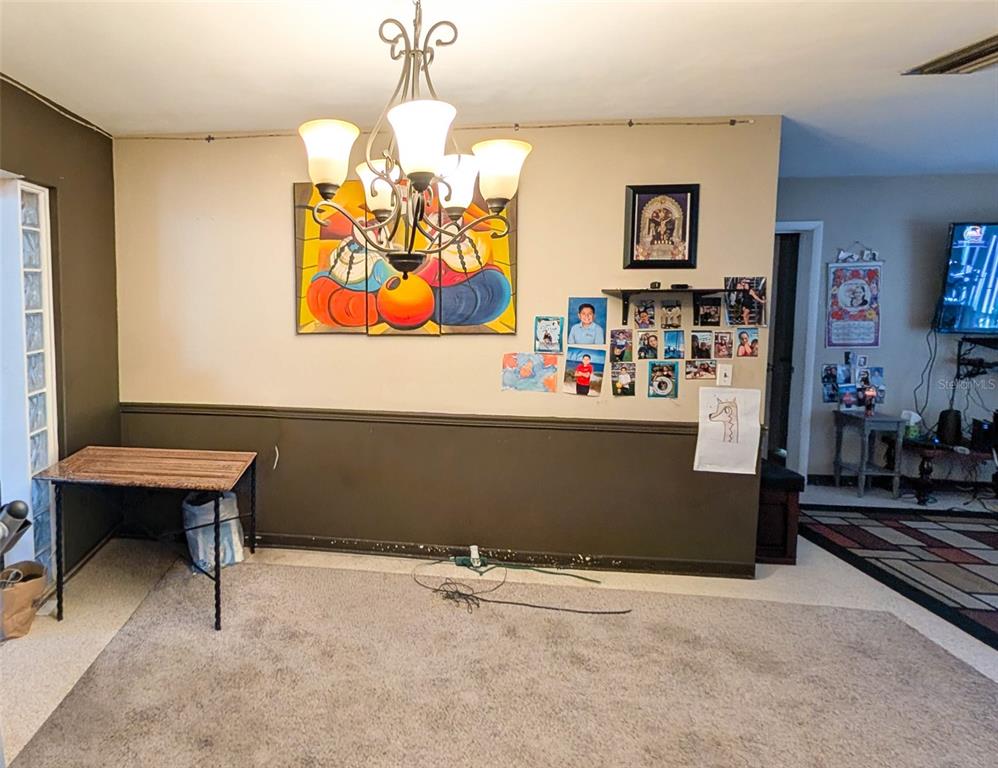 A dining room features a chandelier, a colorful wall painting, and a small desk — 1590 PEACEFUL LANE N, CLEARWATER, FL