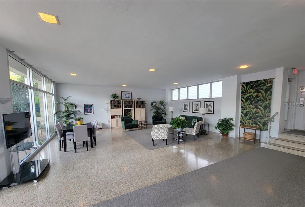 A spacious, open-concept room features terrazzo flooring, large windows, a dining area, and lounge seating — 750 BURLINGTON AVENUE N UNIT 3H, ST PETERSBURG, FL