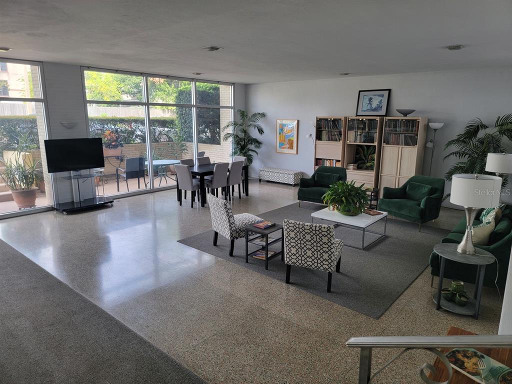 A spacious living and dining area features floor-to-ceiling windows, terrazzo flooring, and mid-century decor — 750 BURLINGTON AVENUE N UNIT 3H, ST PETERSBURG, FL