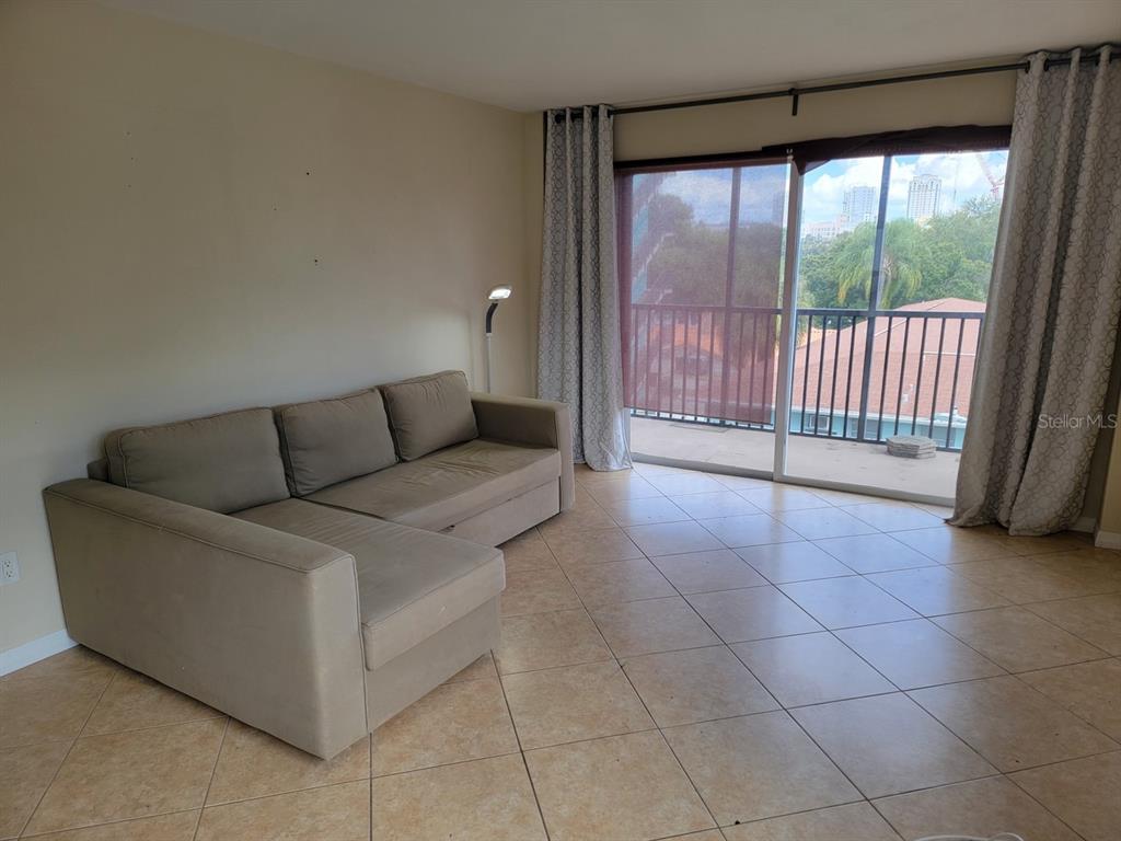 A living room features a beige sectional sofa, tile flooring, and a sliding glass door balcony — 750 BURLINGTON AVENUE N UNIT 3H, ST PETERSBURG, FL