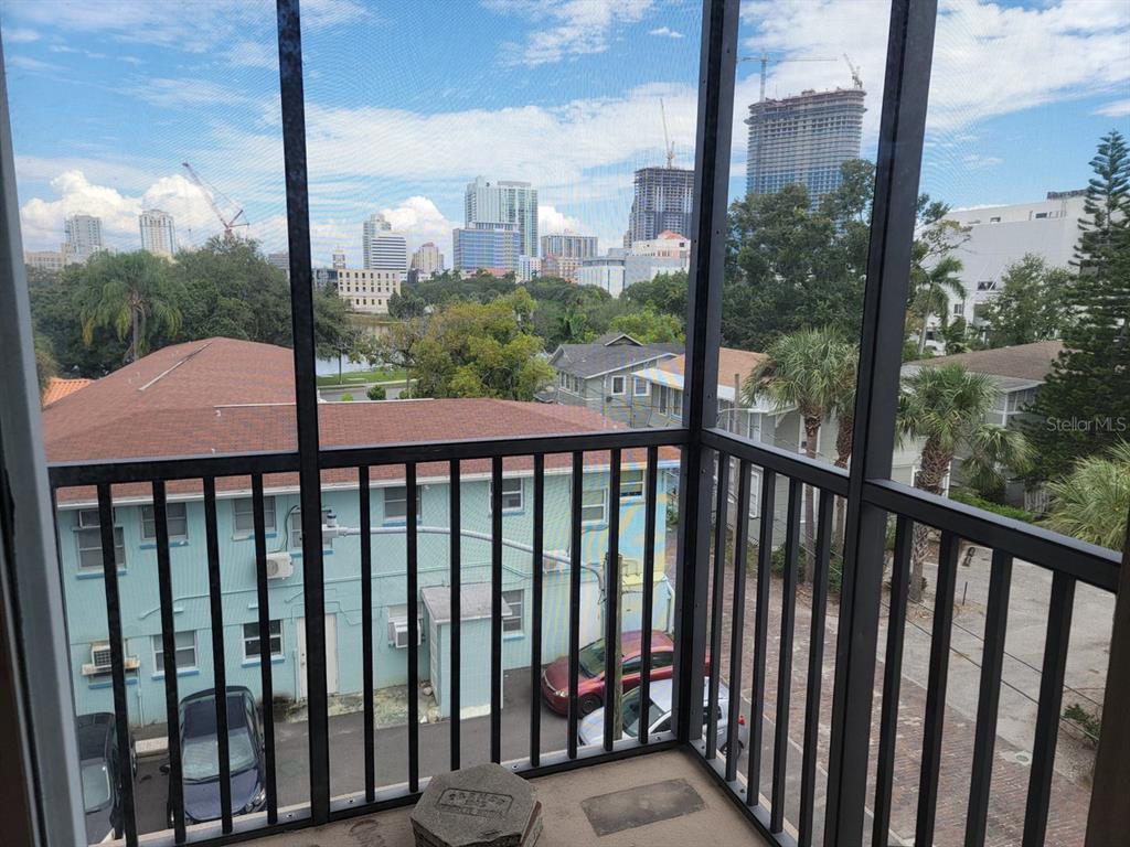 A screened-in balcony overlooks a parking area, nearby houses, and a distant city skyline — 750 BURLINGTON AVENUE N UNIT 3H, ST PETERSBURG, FL