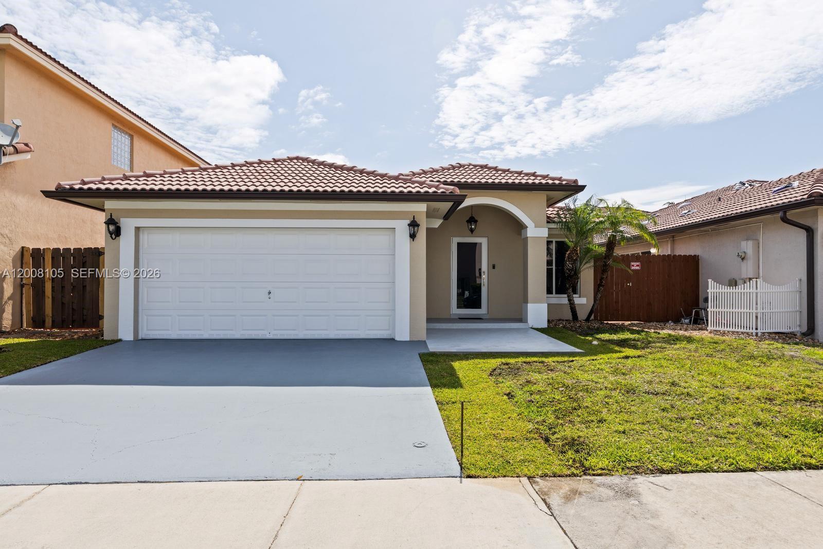A single-story house with a white garage door, tan stucco exterior, and tiled roof — 21505 SW 89th Path, Cutler Bay FL 33189, CUTLER BAY, FL