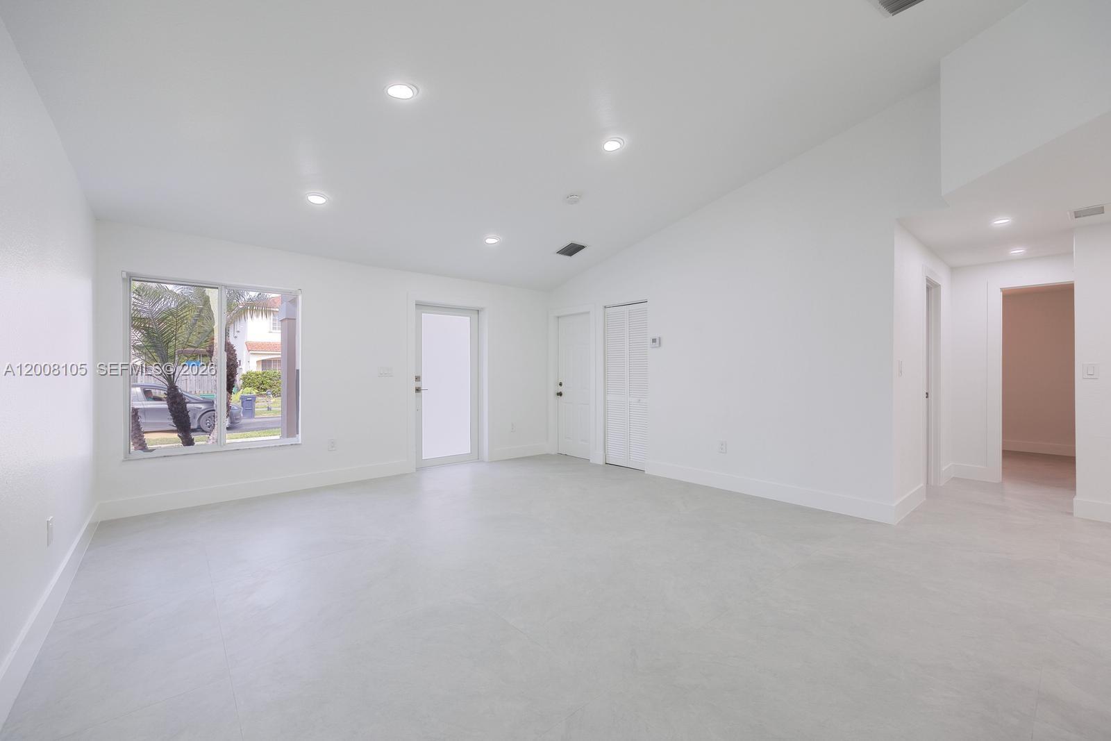 A bright, empty room features white walls, recessed lighting, and light-colored tile flooring — 21505 SW 89th Path, Cutler Bay FL 33189, CUTLER BAY, FL