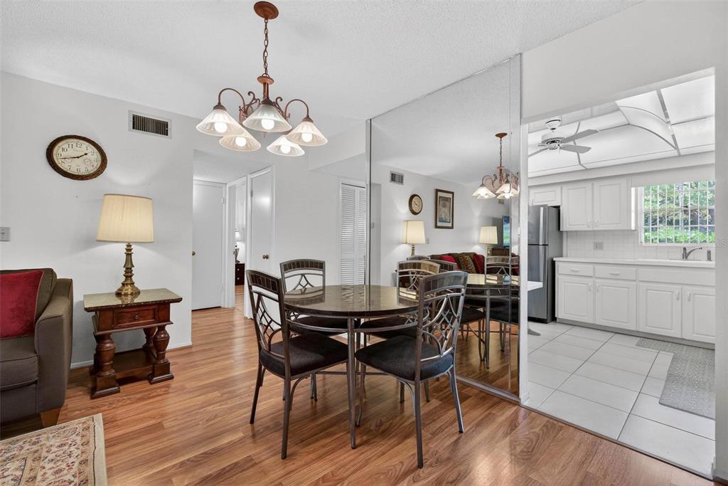 A dining area with a round table, metal chairs, and a mirrored wall beside a kitchen — 2440 WORLD PARKWAY BOULEVARD UNIT 6, CLEARWATER, FL