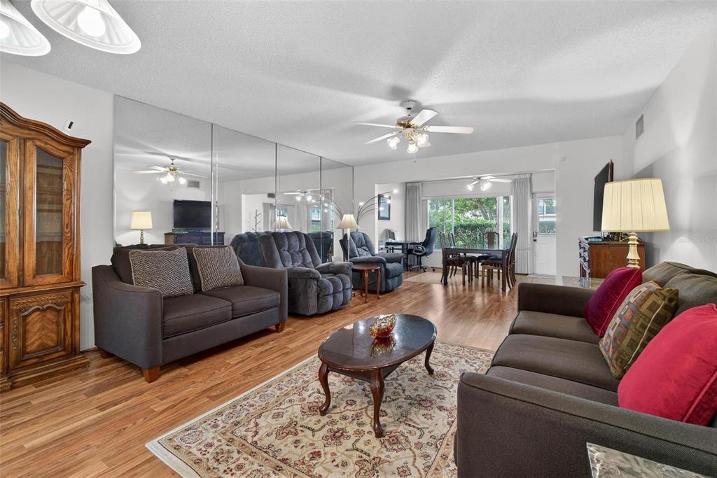 A living room features wood-look flooring, a mirrored wall, and two dark sofas — 2440 WORLD PARKWAY BOULEVARD UNIT 6, CLEARWATER, FL