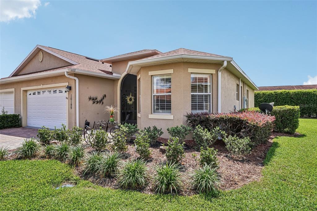 The exterior of a tan, single-story house features a two-car garage and landscaped front yard — 10199 MAINSAIL DRIVE, OXFORD, FL