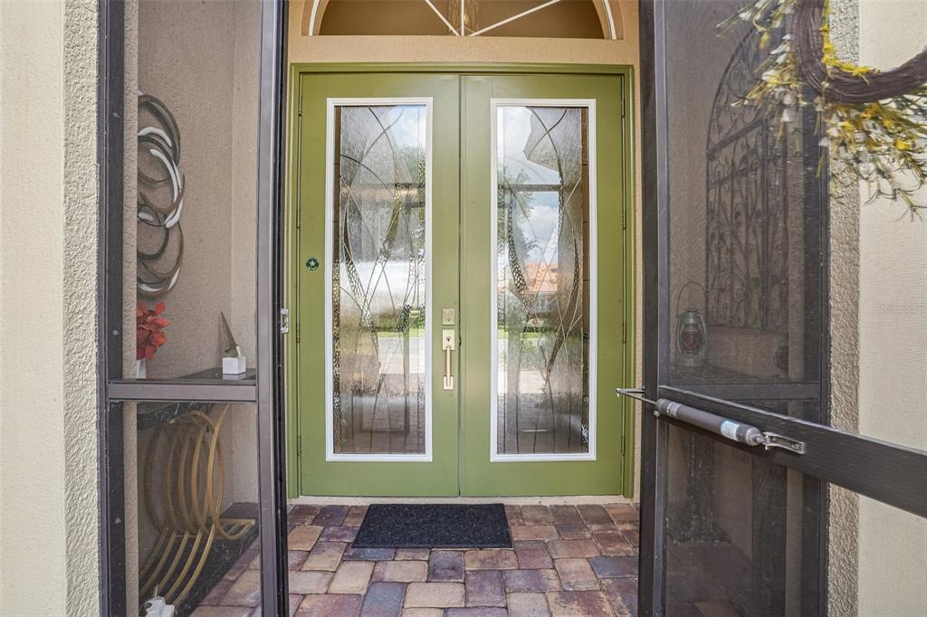 A view through a screen door at a double front door with glass inserts — 10199 MAINSAIL DRIVE, OXFORD, FL