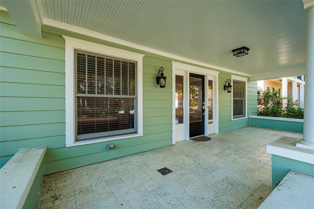 A covered porch with light green siding, a black front door, and tiled flooring — 756 17TH AVENUE NE, ST PETERSBURG, FL