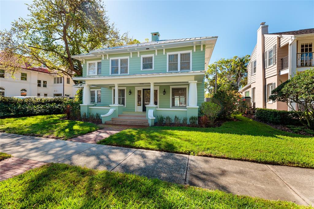 A two-story green house with a front porch and white trim sits behind a lawn — 756 17TH AVENUE NE, ST PETERSBURG, FL