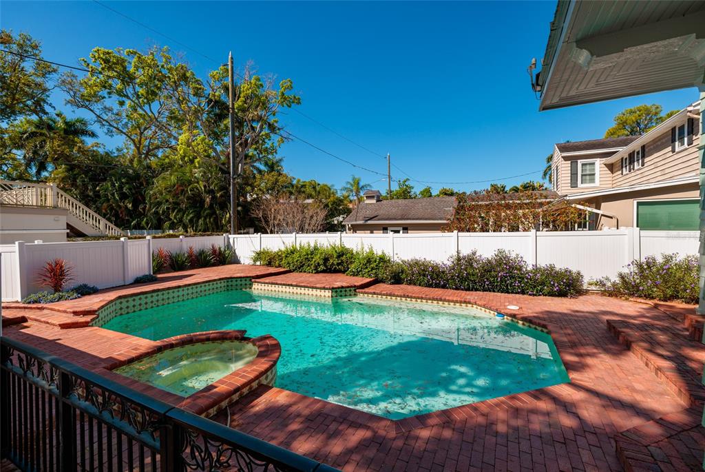 A backyard swimming pool and attached spa are surrounded by a red brick patio — 756 17TH AVENUE NE, ST PETERSBURG, FL