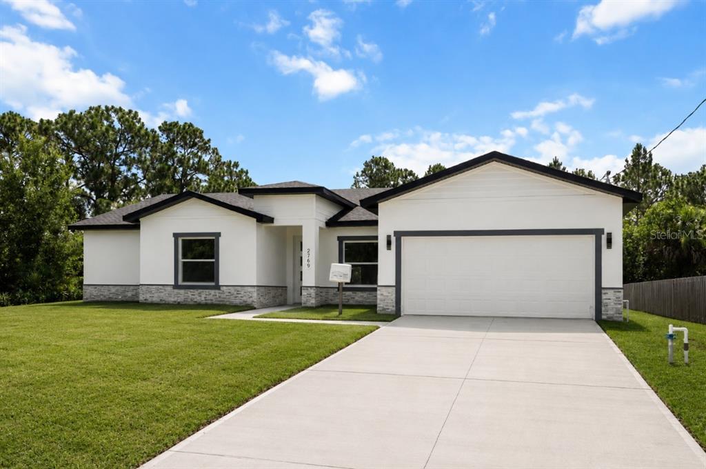 A single-story house with white stucco walls, stone accents, and a two-car garage — 2769 HAGUE STREET SW, PALM BAY, FL