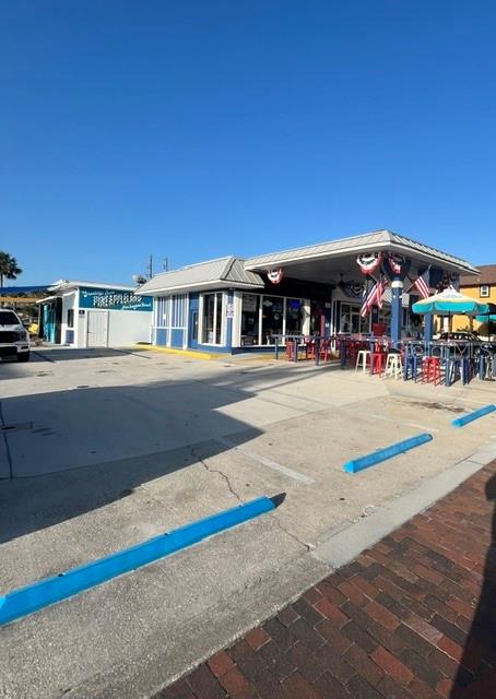 A commercial building with a covered outdoor seating area and a parking lot in front — 323 FLAGLER AVENUE, NEW SMYRNA BEACH, FL