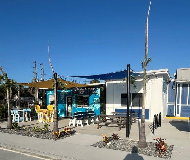 A small commercial building features a blue exterior, outdoor seating, and shade sails — 323 FLAGLER AVENUE, NEW SMYRNA BEACH, FL