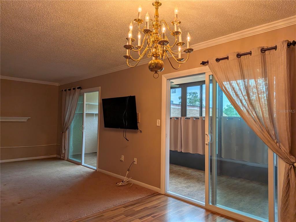 A dining area with a chandelier, carpeted living space, and sliding glass doors to a porch — 2400 FOREST DRIVE UNIT 261, INVERNESS, FL
