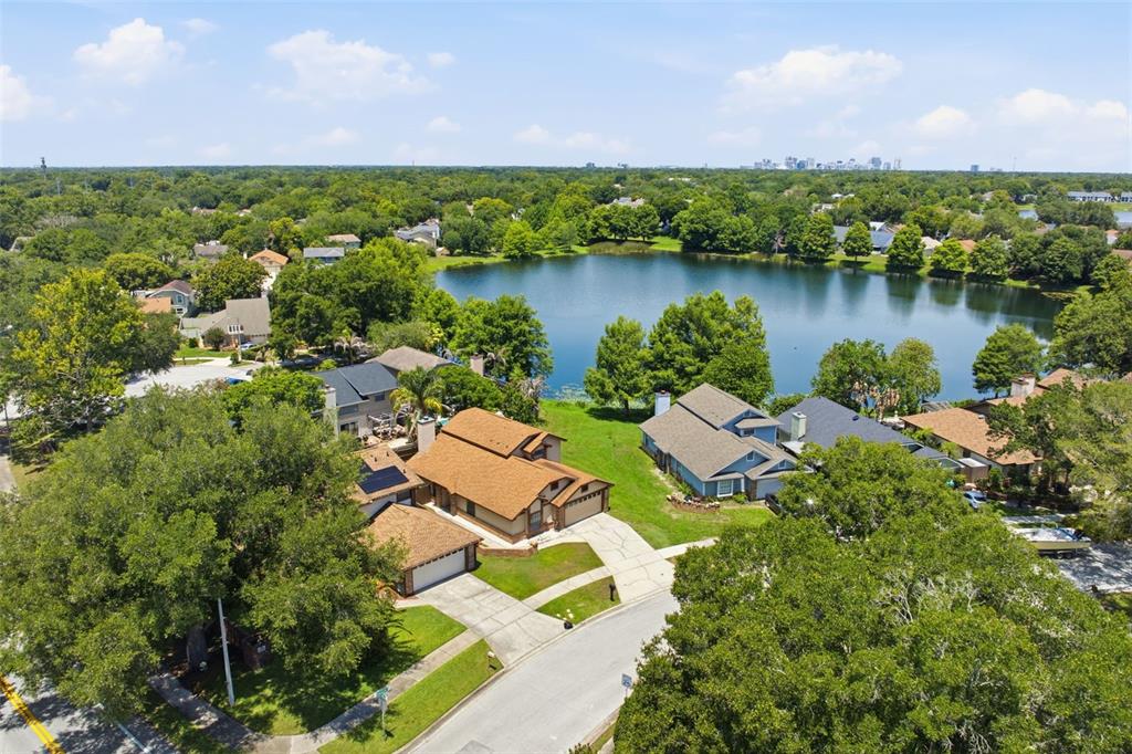 An aerial view shows suburban houses near a lake with a city skyline in distance — 3500 CHATSWORTH LANE, ORLANDO, FL