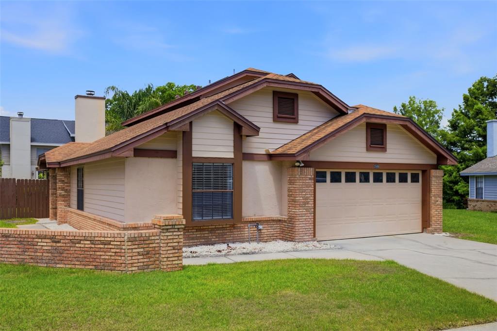 A single-story house with tan siding, brick accents, a two-car garage, and a low-pitched roof — 3500 CHATSWORTH LANE, ORLANDO, FL