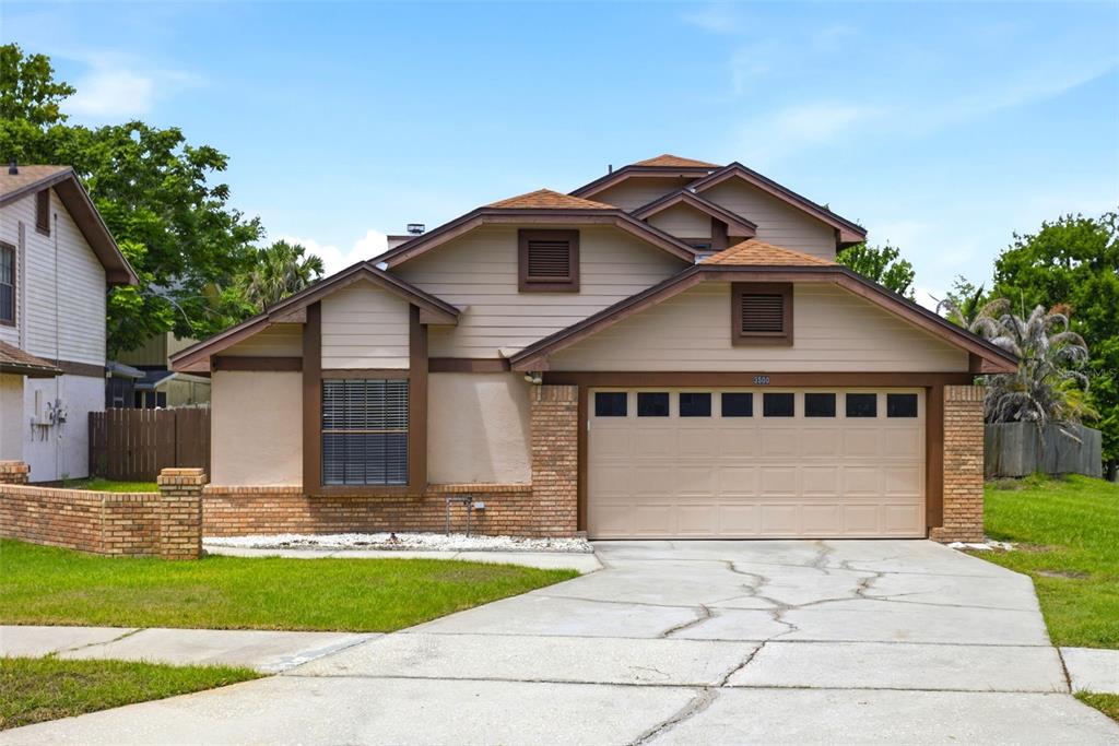A tan, two-story house with a brick base, brown trim, and a two-car garage — 3500 CHATSWORTH LANE, ORLANDO, FL