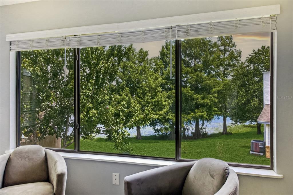 Two armchairs face a large window overlooking a grassy yard and a lake with trees — 3500 CHATSWORTH LANE, ORLANDO, FL