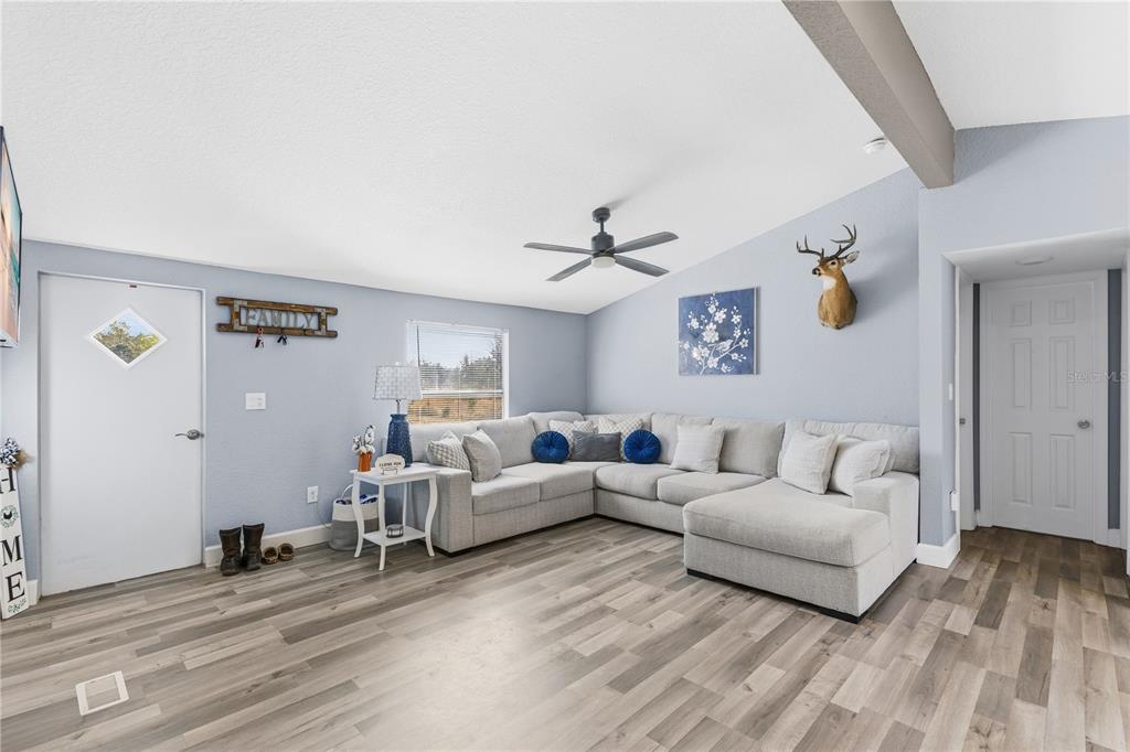 A living room features a light gray sectional sofa, wood-look flooring, and a deer head mount — 10810 SPORTSMAN TRAIL, LAKELAND, FL
