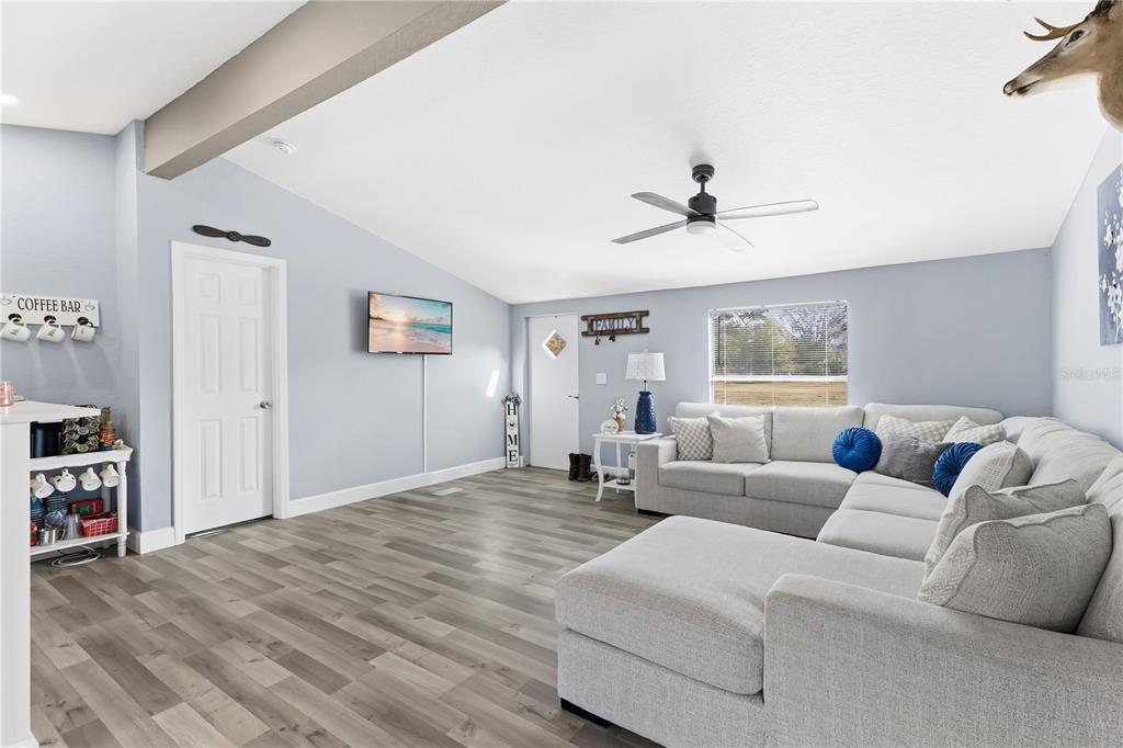 A living room features light blue walls, gray wood-look flooring, and a large sectional sofa — 10810 SPORTSMAN TRAIL, LAKELAND, FL