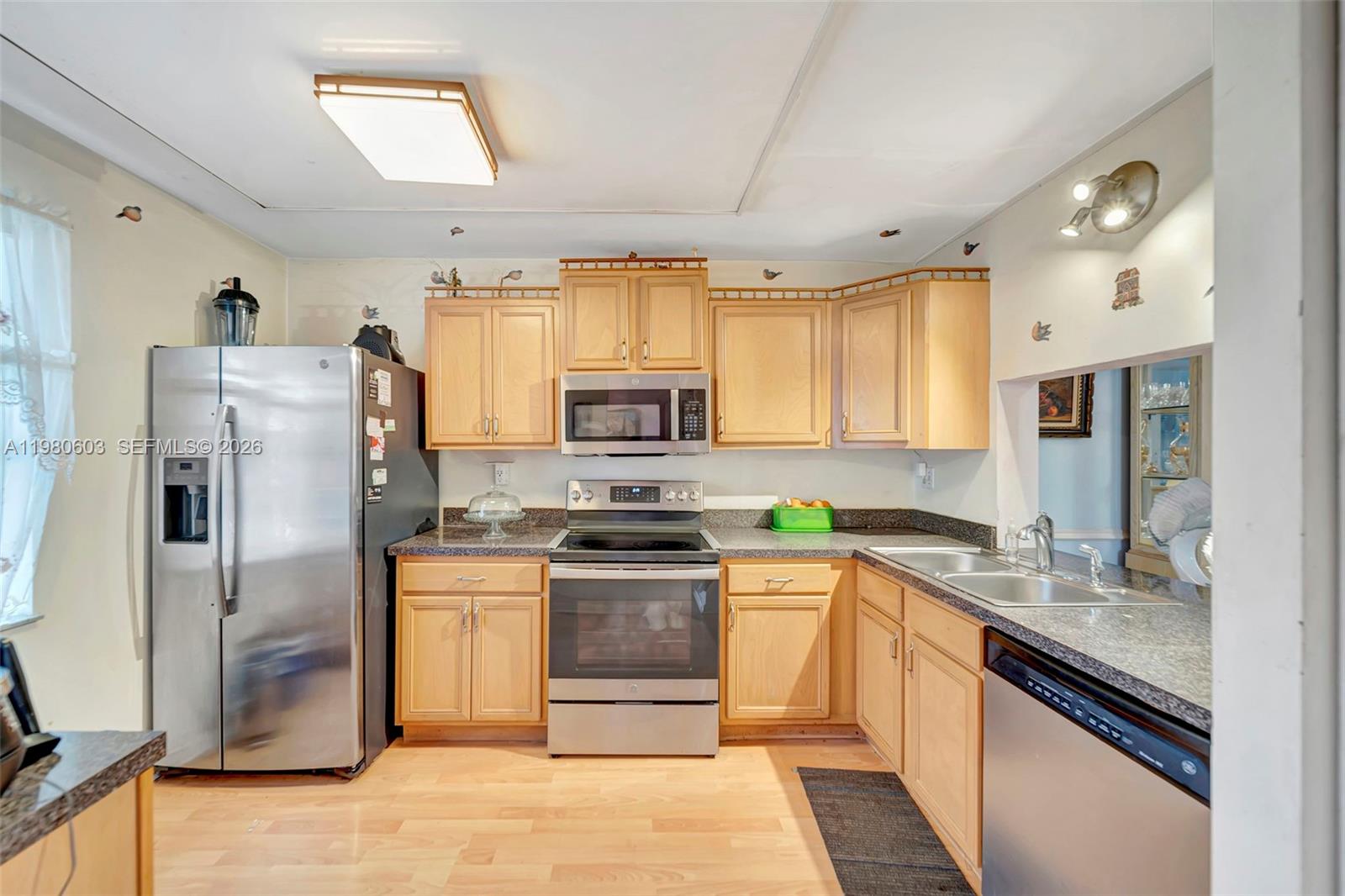 A kitchen features light wood cabinets, stainless steel appliances, and dark granite countertops — 3940 Inverrary Blvd # A, Lauderhill FL 33319, LAUDERHILL, FL