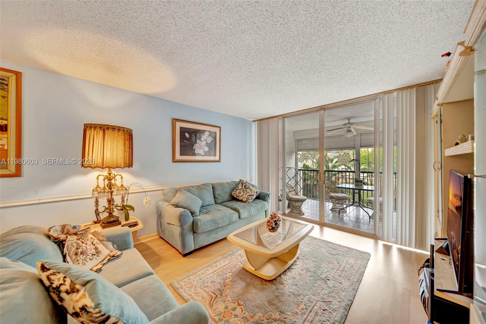 A living room features light blue walls, two sofas, a coffee table, and a balcony — 3940 Inverrary Blvd # A, Lauderhill FL 33319, LAUDERHILL, FL