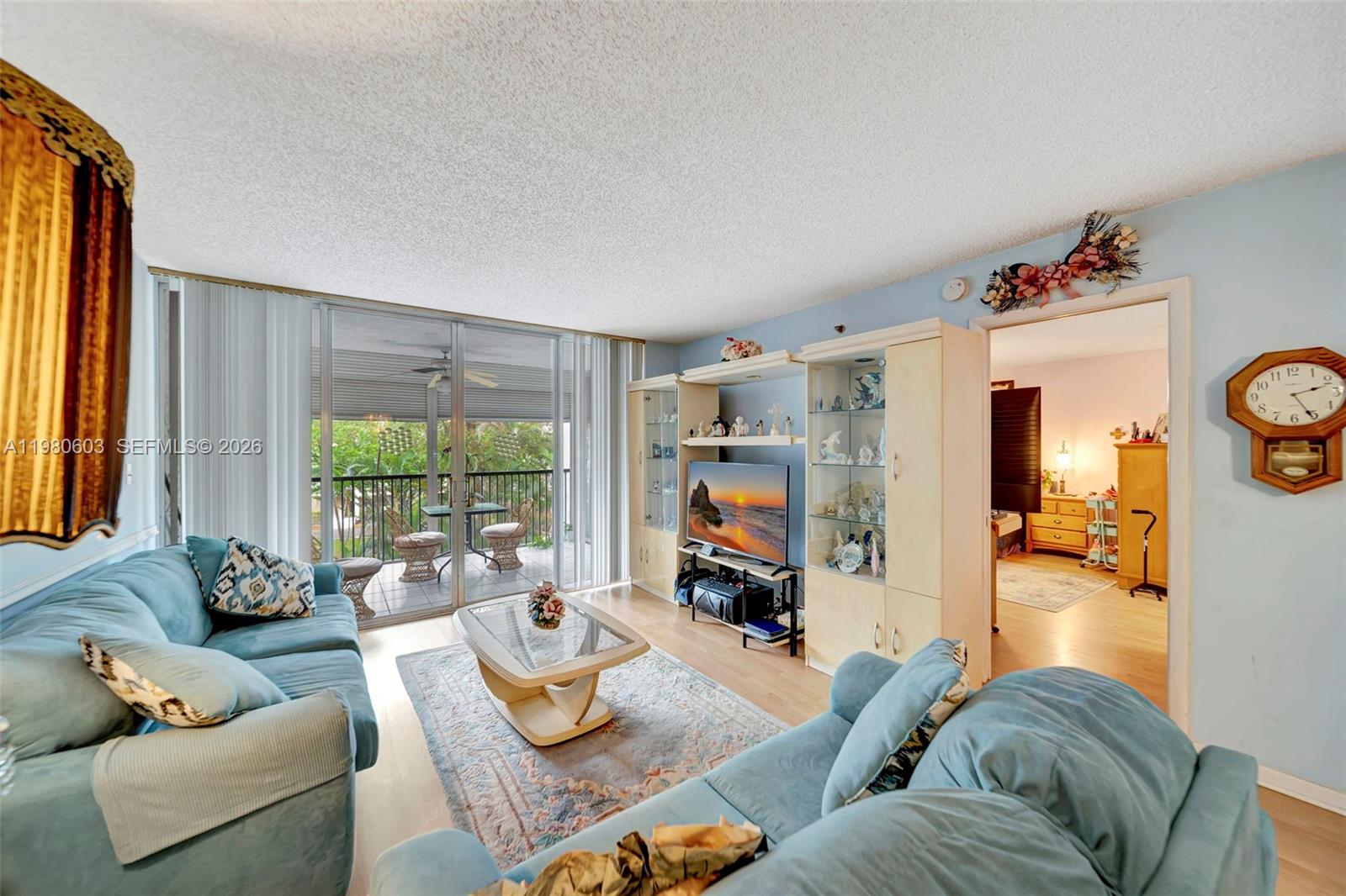 A living room features two blue sofas, a glass coffee table, and a balcony view — 3940 Inverrary Blvd # A, Lauderhill FL 33319, LAUDERHILL, FL
