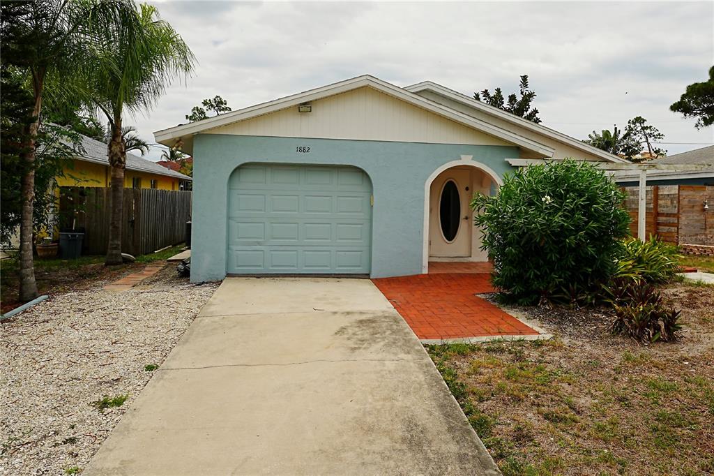 A light blue, single-story house with a garage, arched entryway, and a concrete driveway — 1882 RITA STREET, SARASOTA, FL