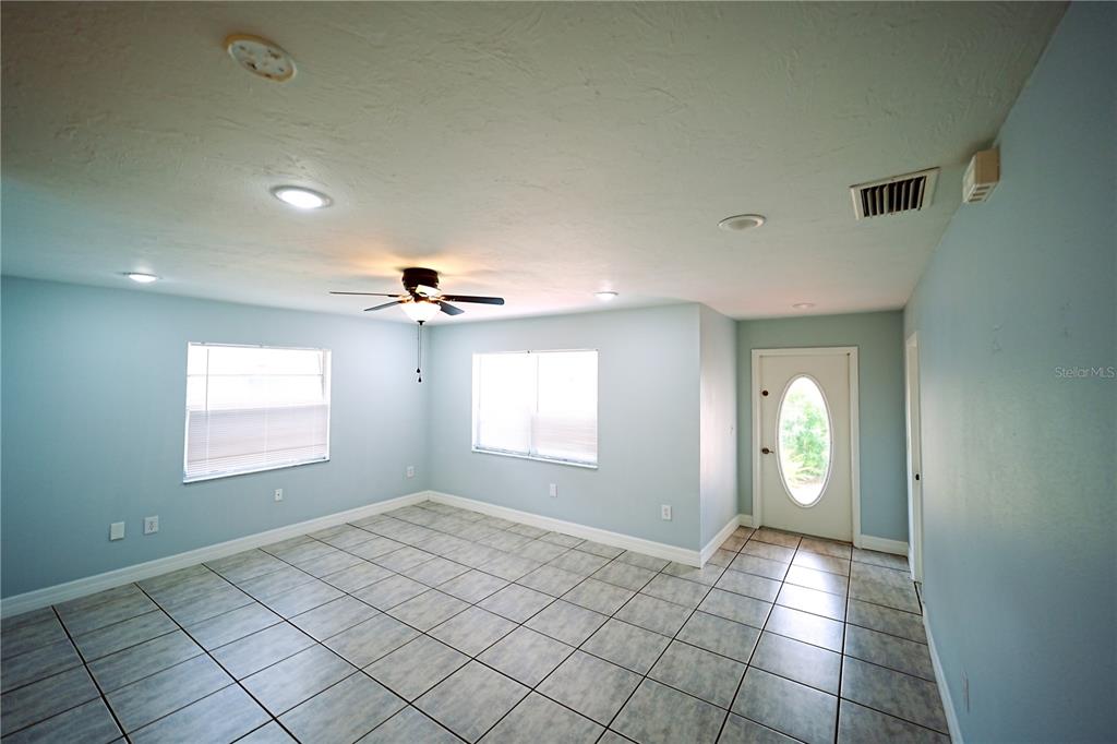 A bright room with light blue walls, tile flooring, a ceiling fan, and an entry door — 1882 RITA STREET, SARASOTA, FL